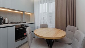 Une cuisine moderne avec une table ronde en bois et quatre chaises, une cuisinière à gaz et un four encastré.