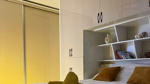 Ein modernes Schlafzimmer mit einem großen Bett, einem Einbauschrank und einem Nachttisch mit Dekoration.