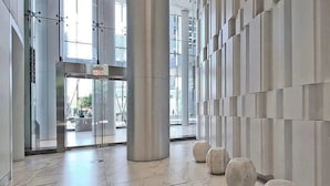 A modern lobby with a marble floor, large columns, and a glass entrance.