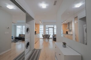 Una cocina moderna con comedor, lavadora y un amplio ventanal que proporciona luz natural.