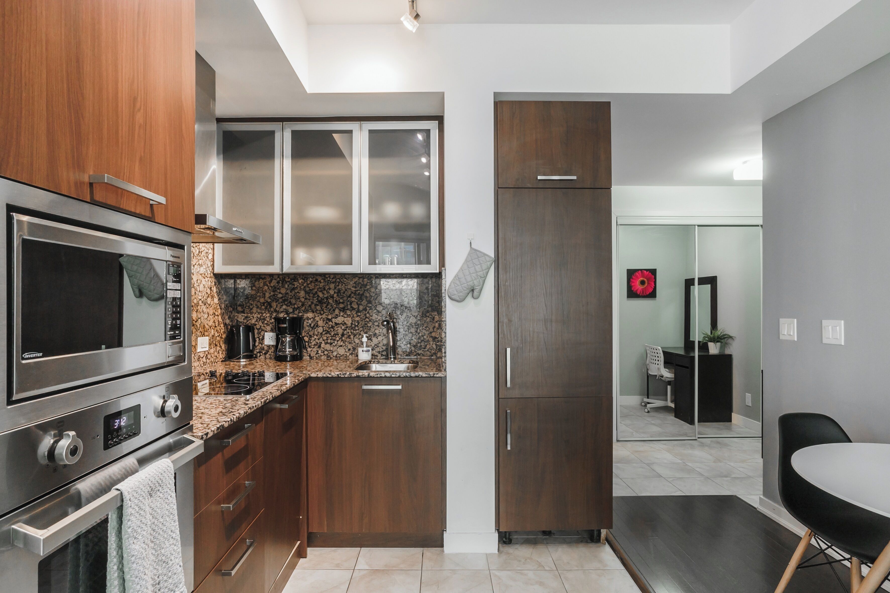 A modern kitchen with stainless steel appliances, wooden cabinets, and a granite countertop.