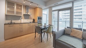 A modern kitchen with a dining area, large windows, and a sofa.