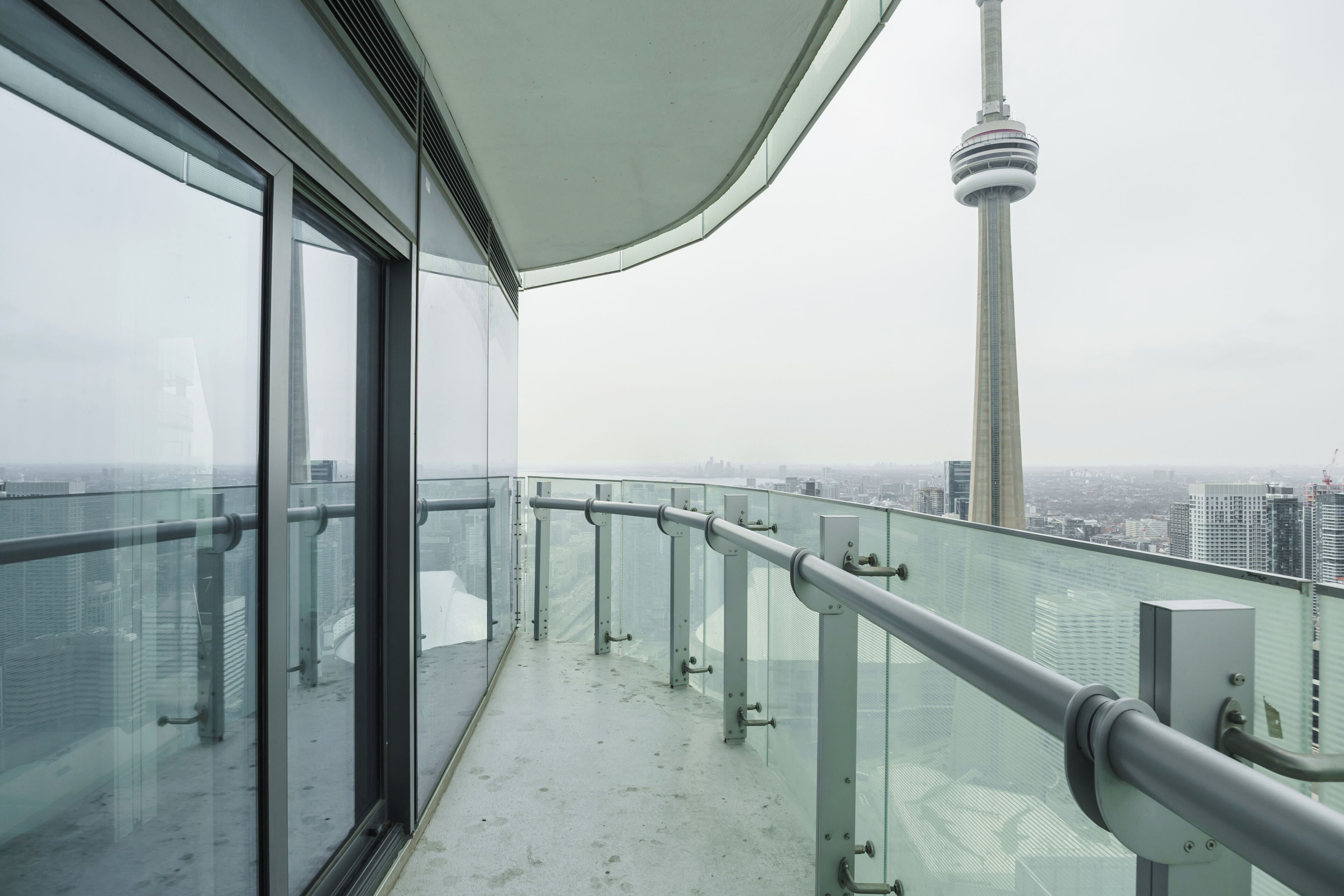Een hoog gebouw met een glazen balkon dat uitkijkt over een stadsgezicht, waaronder een opvallende toren.