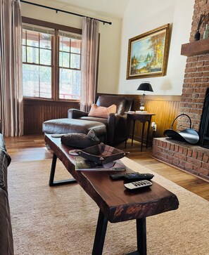 A cozy living room with a leather sofa, a wooden coffee table, and a fireplace.