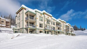Een hotel met meerdere verdiepingen en balkons, gelegen op een besneeuwde helling.