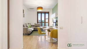 A modern living room with a sofa, dining table, and chairs. - The Remembrances Suite (Milan)