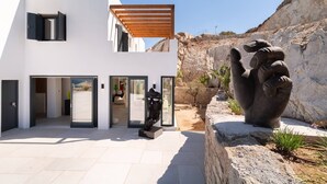Et moderne hus med en patio, en skulptur og udsigt til det klippefyldte landskab.