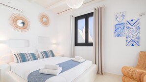 Una habitación de hotel moderna con una cama grande, dos espejos en la pared, una ventana con cortinas y dos obras de arte en la pared.