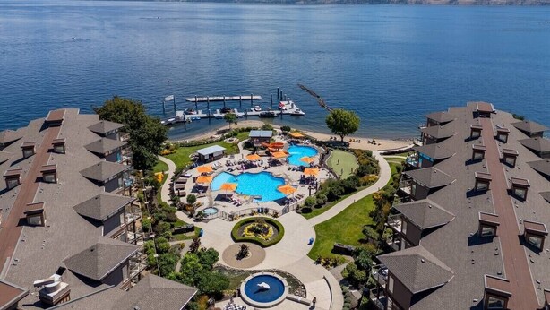 A resort with multiple swimming pools, a dock, and a view of a lake and mountains. - Lakefront Resort Condo with Pool (West Kelowna)