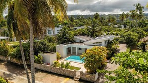 A modern resort with a pool, surrounded by lush greenery and palm trees. - Lux Villa Playa Bonita (Las Terrenas)
