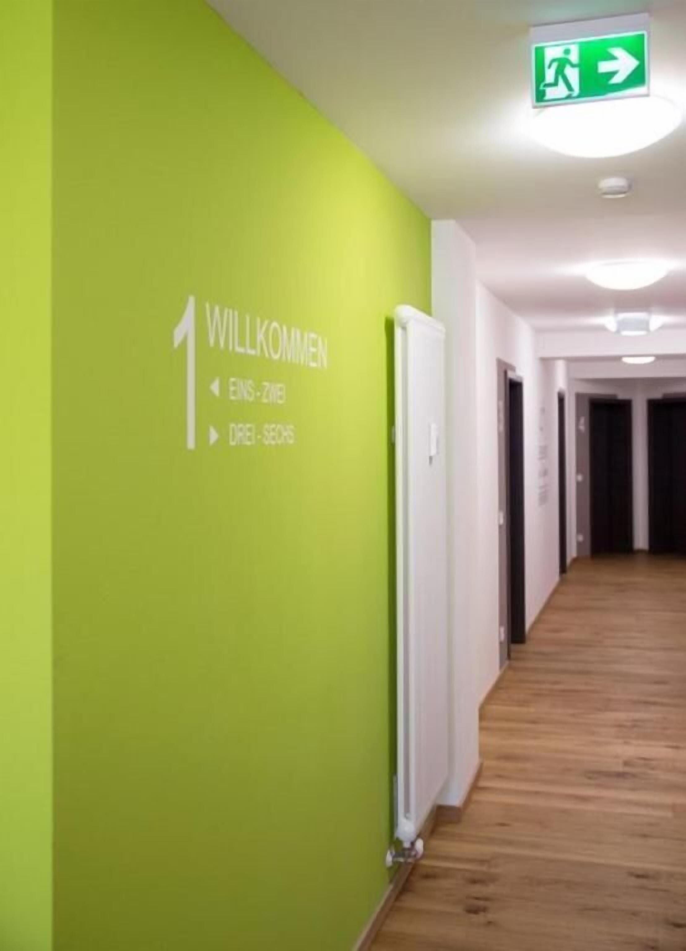 Un couloir avec un mur vert et un panneau indiquant l’emplacement de la réception.
