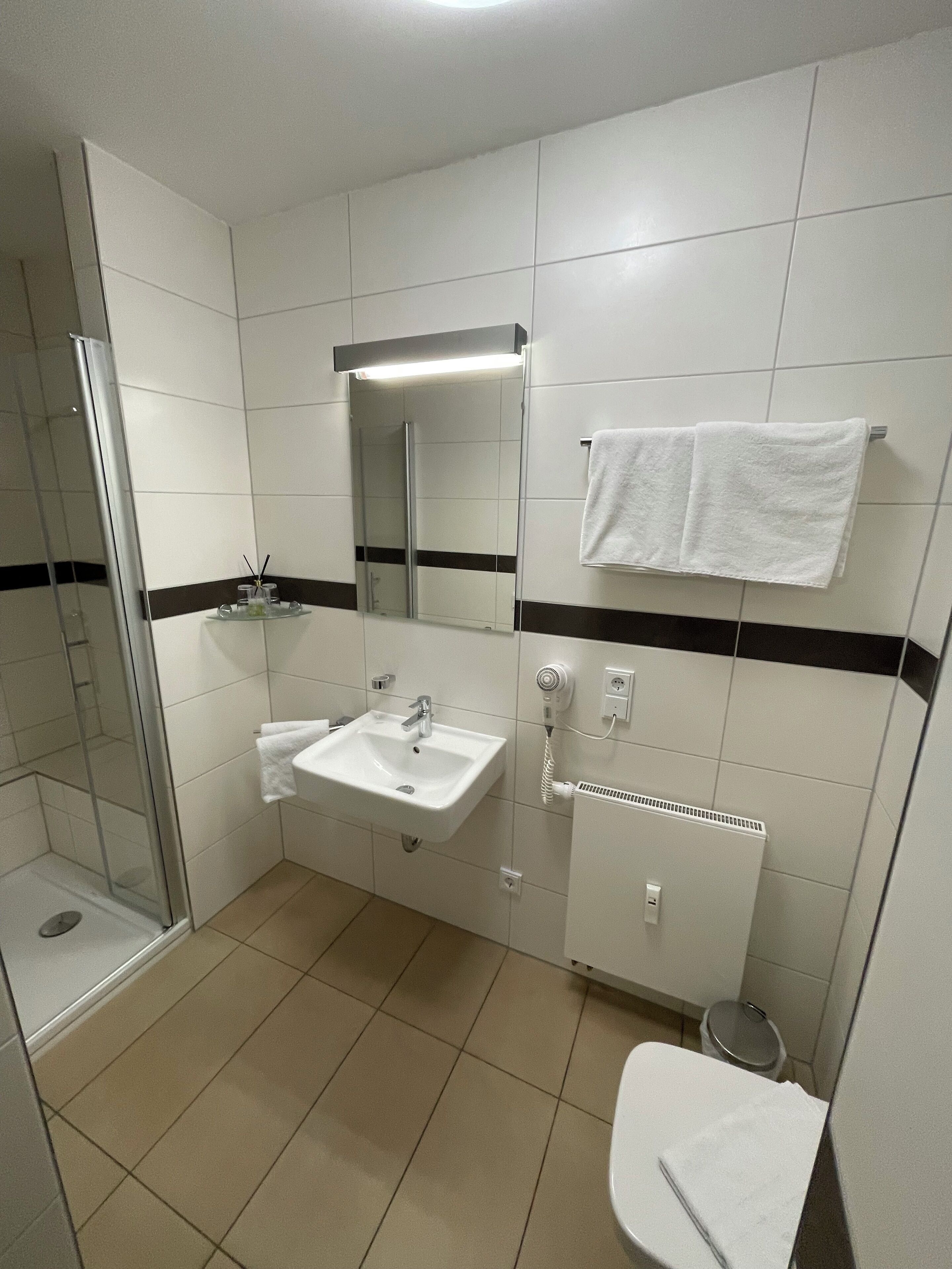 Un baño con cabina de ducha de vidrio, un lavabo con espejo y un inodoro.