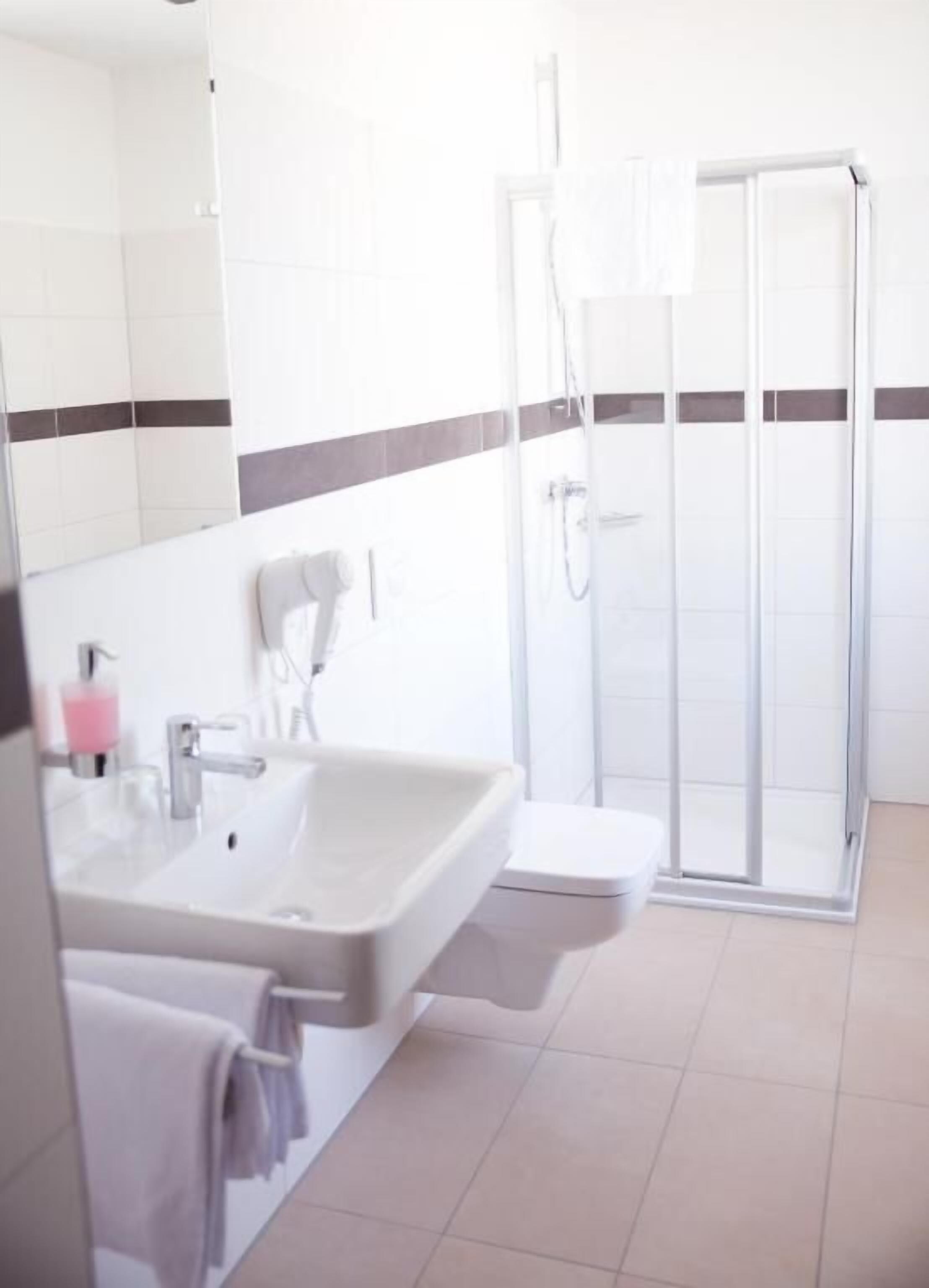 A bathroom with a sink, mirror, and shower.