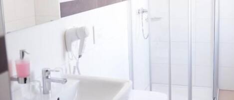 A bathroom with a sink, mirror, and shower.