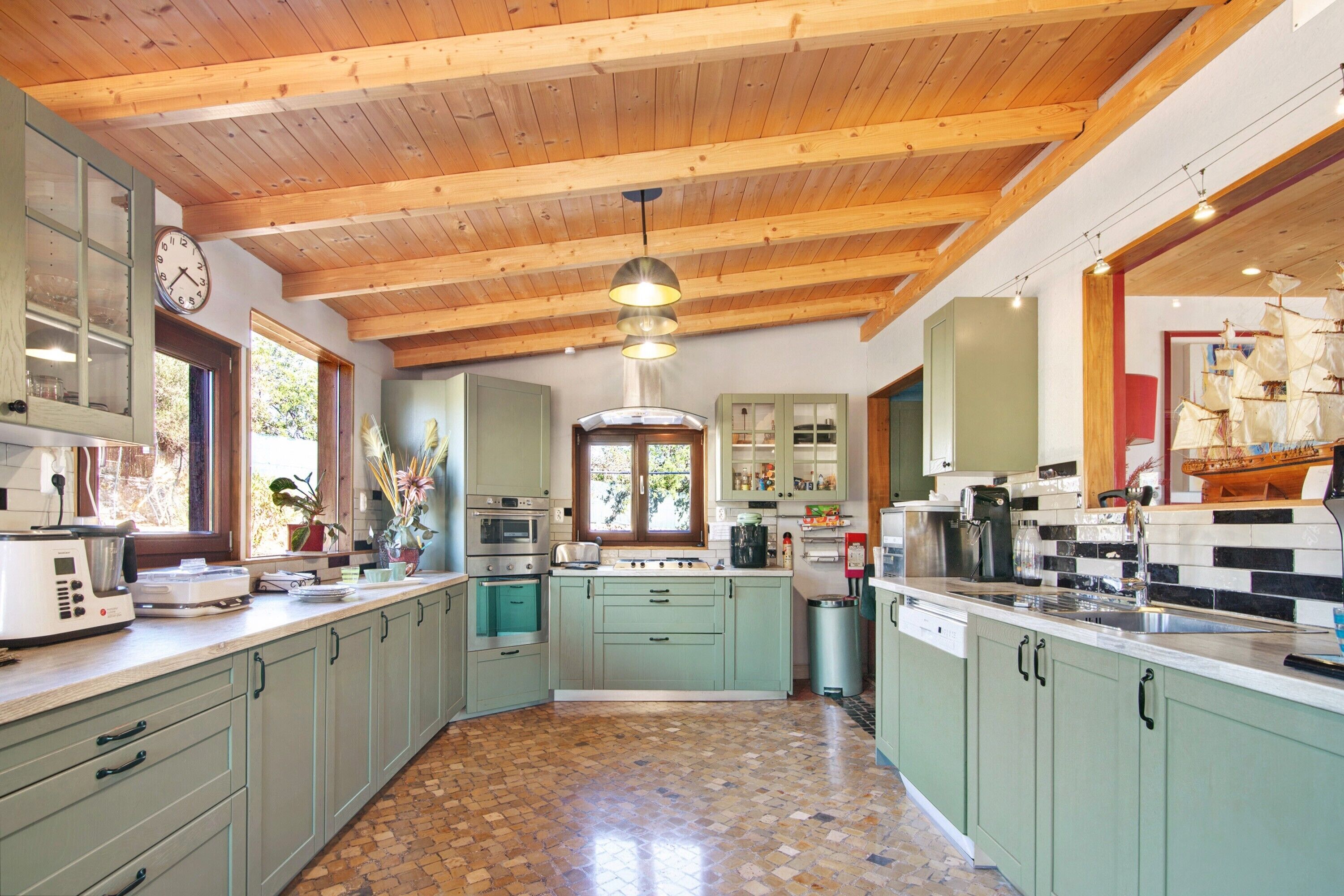 A spacious kitchen with wooden beams, a central island, and various appliances.