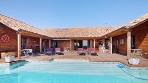 Ein Poolbereich mit Holzterrasse, Liegestühlen und einem klaren, blauen Pool.
