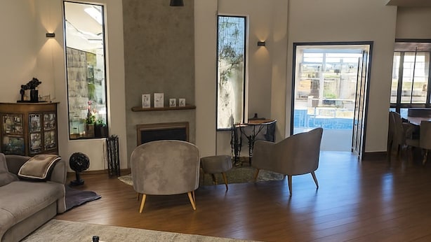 A spacious living room with a large sofa, two armchairs, a coffee table, and a fireplace. There are large windows providing natural light and a view of the outside. - Luxury House in Gated Community in Metropolitan Area (Mogi das Cruzes)