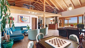 A spacious living area with a high ceiling, wooden beams, a billiards table, and a view through large windows. - Sevilha Room – Naturist B&B for Couples (Monte da Charneca)