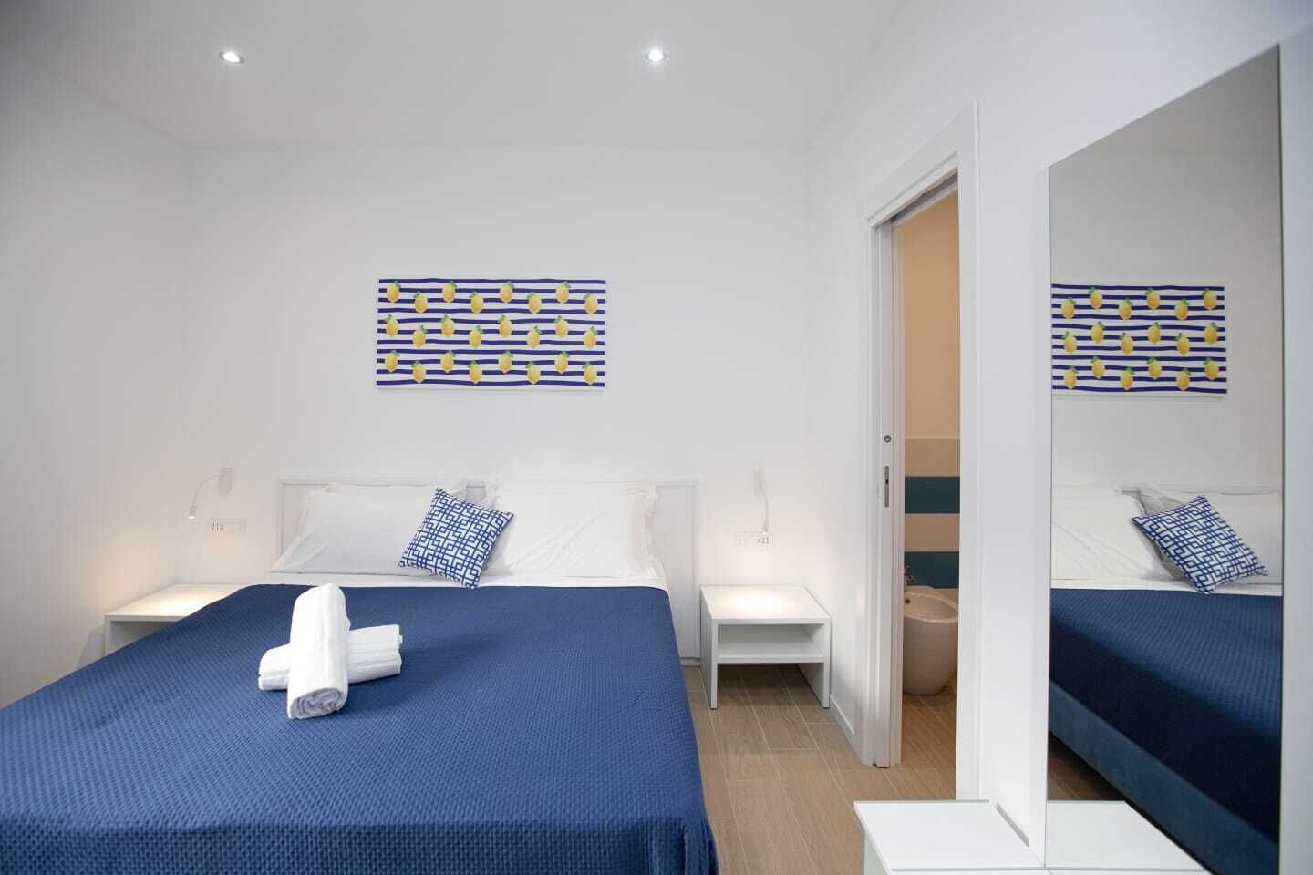 A modern hotel room with two beds, a large mirror, and decorative wall art.