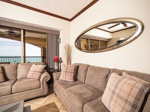 Ein Wohnzimmer mit einem großen Spiegel, zwei Sofas, einem kleinen Tisch und Blick aufs Meer.