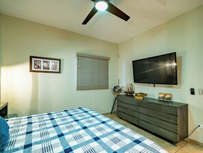 Ein Schlafzimmer mit Bett, Kommode, Fernseher und Deckenventilator.