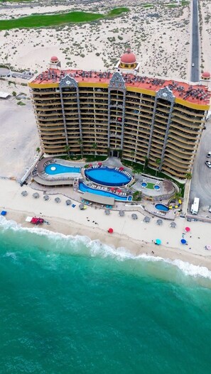 Ein großes Hotel mit mehreren Balkonen, einem zentral gelegenen Pool und einer Strandlage.