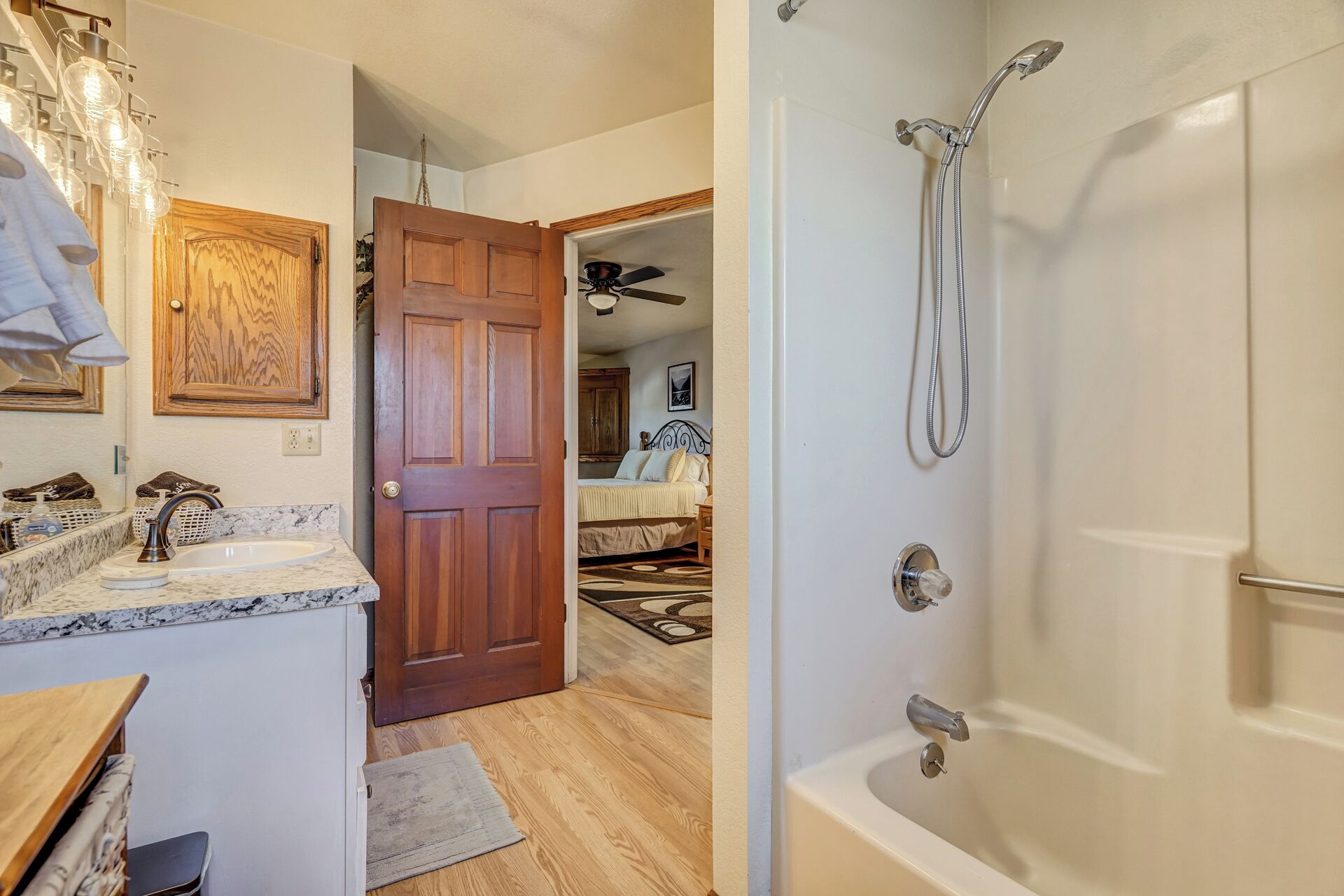 Une salle de bain avec une douche, une porte en bois, un lavabo en marbre et un ventilateur de plafond.