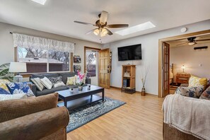 A living room with a sofa, coffee table, and chairs, a TV, and a ceiling fan. - 1729 Arbor Way (Colorado Springs)