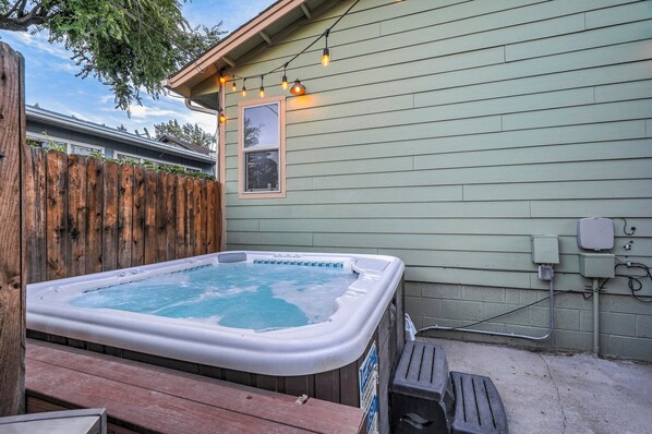 A hot tub in a backyard with a wooden deck, a wooden fence, and a house with siding. - 1014b Swope (Colorado Springs)