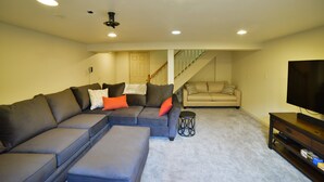 A living room with a sectional sofa, a smaller sofa, a coffee table, and a TV stand. - 1014b Swope (Colorado Springs)