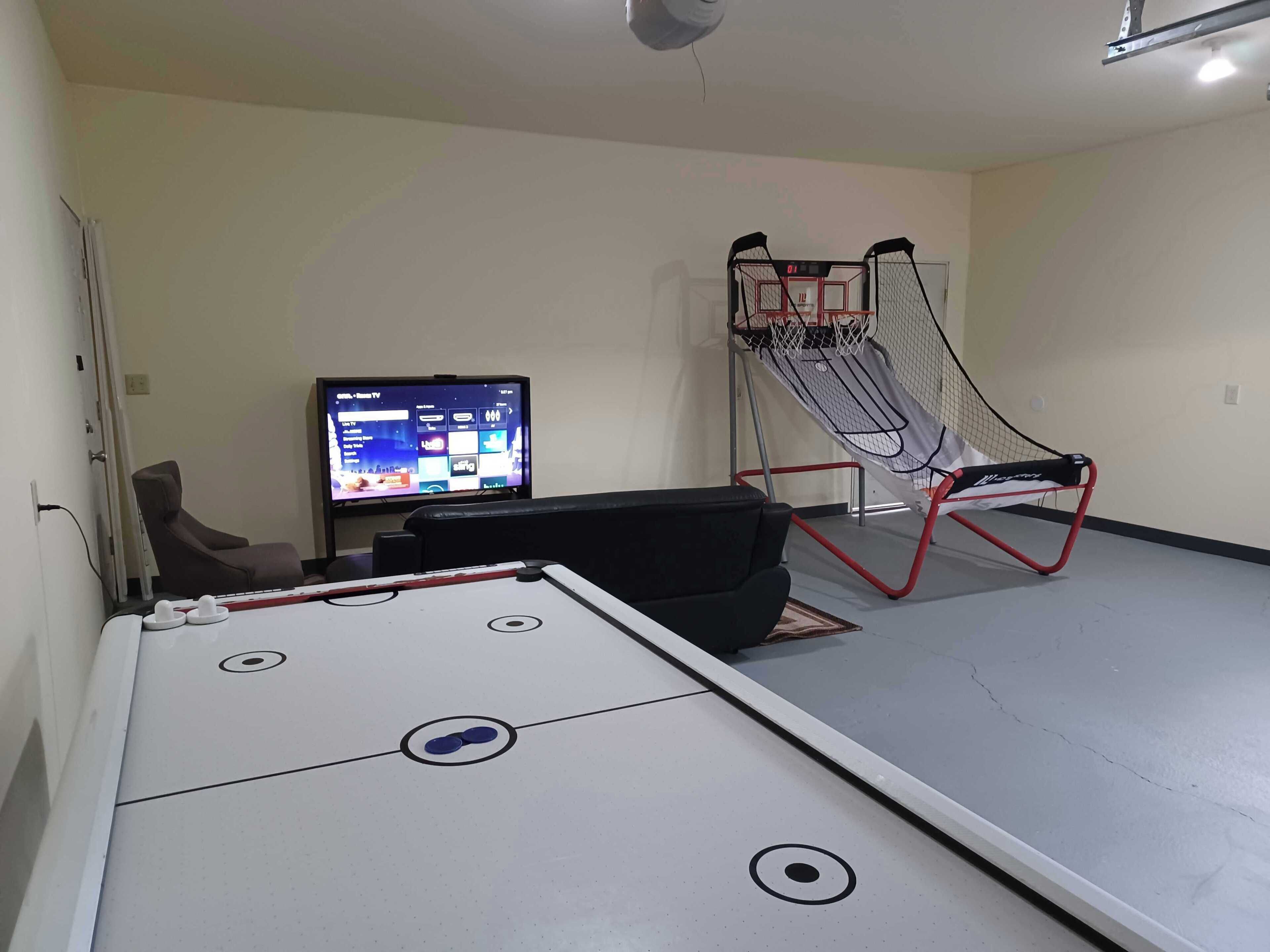 Um quarto com mesa de pebolim, televisão e um cesto de netball.