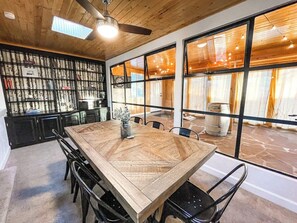 Un comedor con una gran mesa de madera, sillas negras y un ventilador de techo.