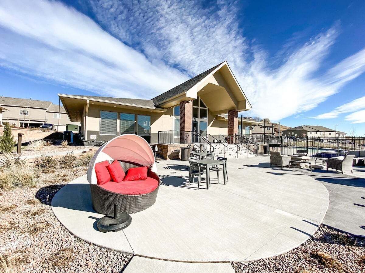 A modern building with a covered patio area, outdoor seating, and a clear sky.