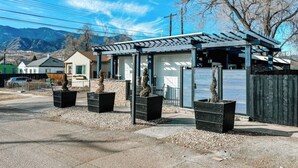 A small, single-story building with a covered patio area, surrounded by a gravel driveway and bordered by a wooden fence. - 2201 W Colorado (Colorado Springs)