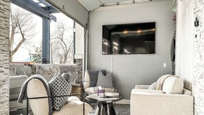 A modern living room with a sofa, armchair, and coffee table. A flat-screen TV is mounted on the wall. - 2201 W Colorado (Colorado Springs)