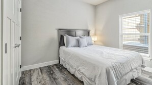 A bedroom with a bed, a headboard, a window with blinds, and a door. - 5370 N Union Unit101 (Colorado Springs)