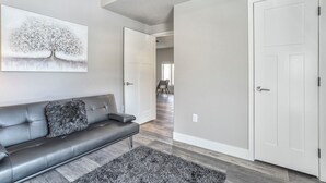 A modern living room with a gray leather sofa, a fluffy gray rug, and a large abstract painting on the wall. - 5370 N Union Unit101 (Colorado Springs)