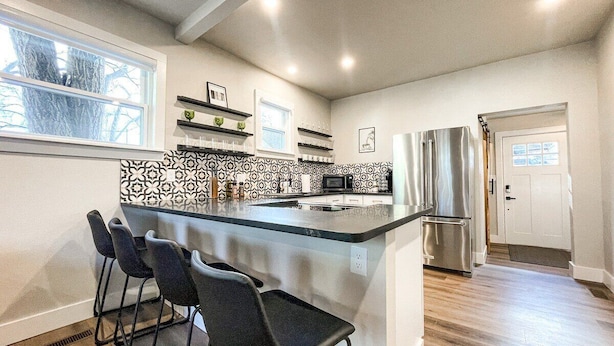 A modern kitchen with a central island, bar stools, a refrigerator, and a microwave. - 22 N Chestnut (Colorado Springs)