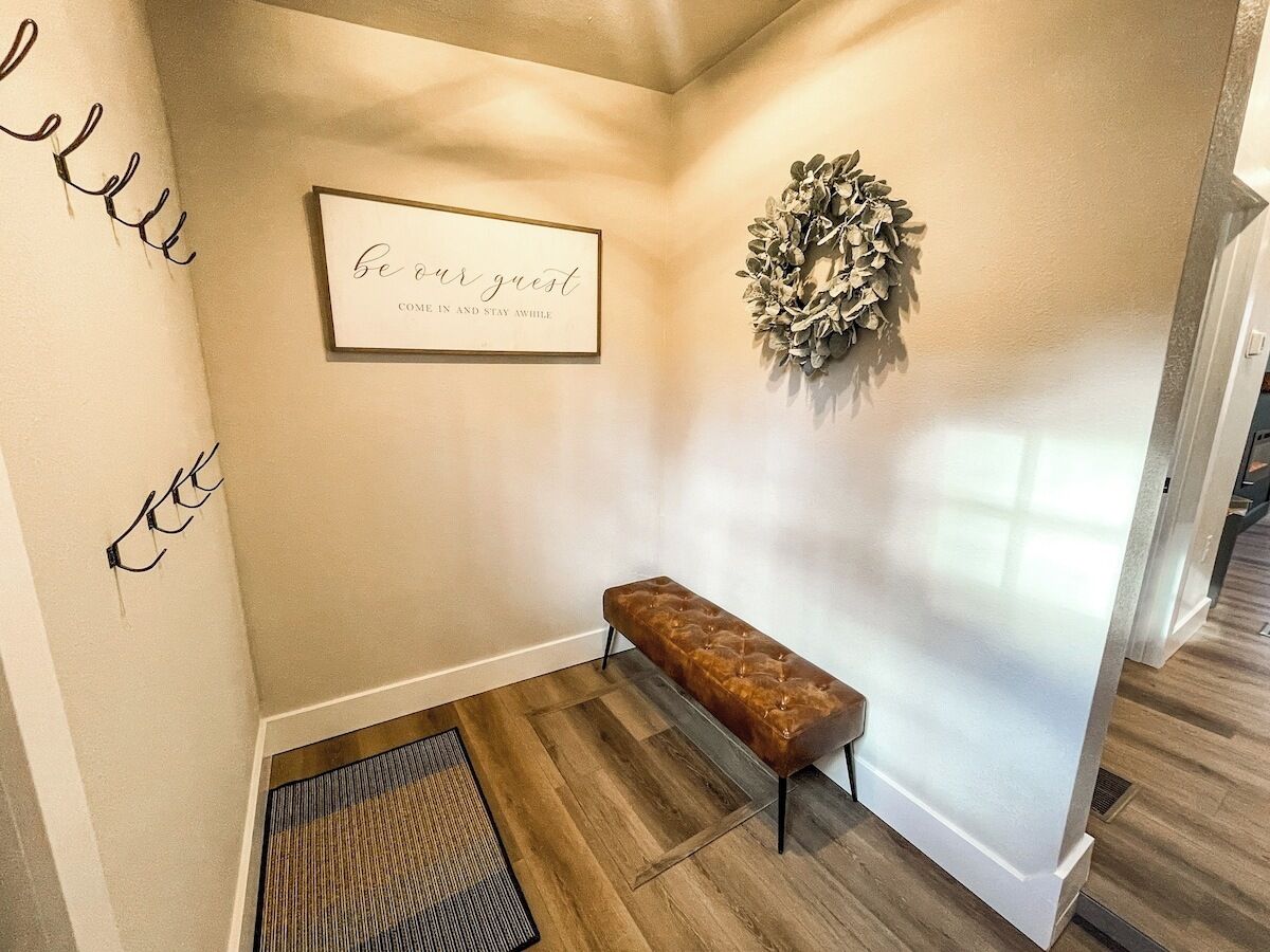 A hallway with a bench, a framed sign, and a decorative wreath.
