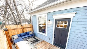 A covered patio with a barbecue grill, a wooden deck, and a blue house with a dark door and windows. - 22 N Chestnut (Colorado Springs)