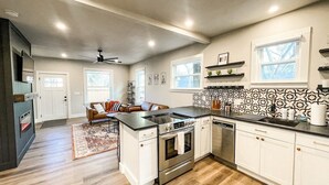 A modern kitchen with a central island, stainless steel appliances, and a patterned backsplash. - 22 N Chestnut (Colorado Springs)