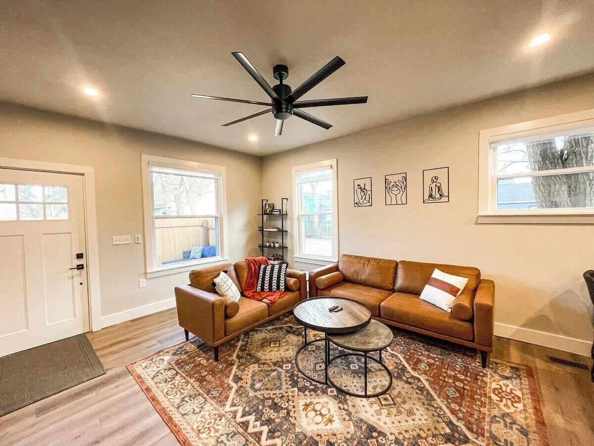 A living room with a brown leather sectional sofa, a coffee table, and a ceiling fan.