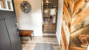 A hallway with a wooden floor, a bench, a door, and a wall-mounted wreath. - 22 N Chestnut (Colorado Springs)