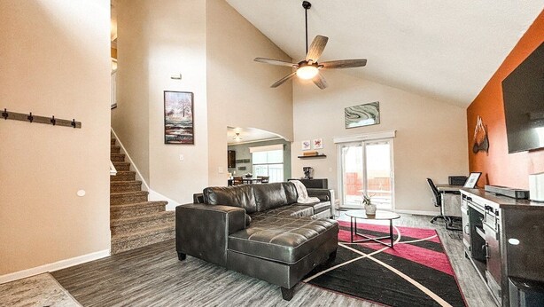 A spacious living area with a leather sofa, a ceiling fan, and a kitchen area with a refrigerator and stove. - 9519 Cool Shadow (Colorado Springs)