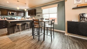A modern kitchen with a central island, bar stools, and a coffee machine. - 9519 Cool Shadow (Colorado Springs)