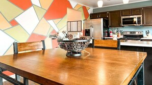 A modern kitchen with dark cabinets, stainless steel appliances, and a colorful geometric wall design. - 9519 Cool Shadow (Colorado Springs)