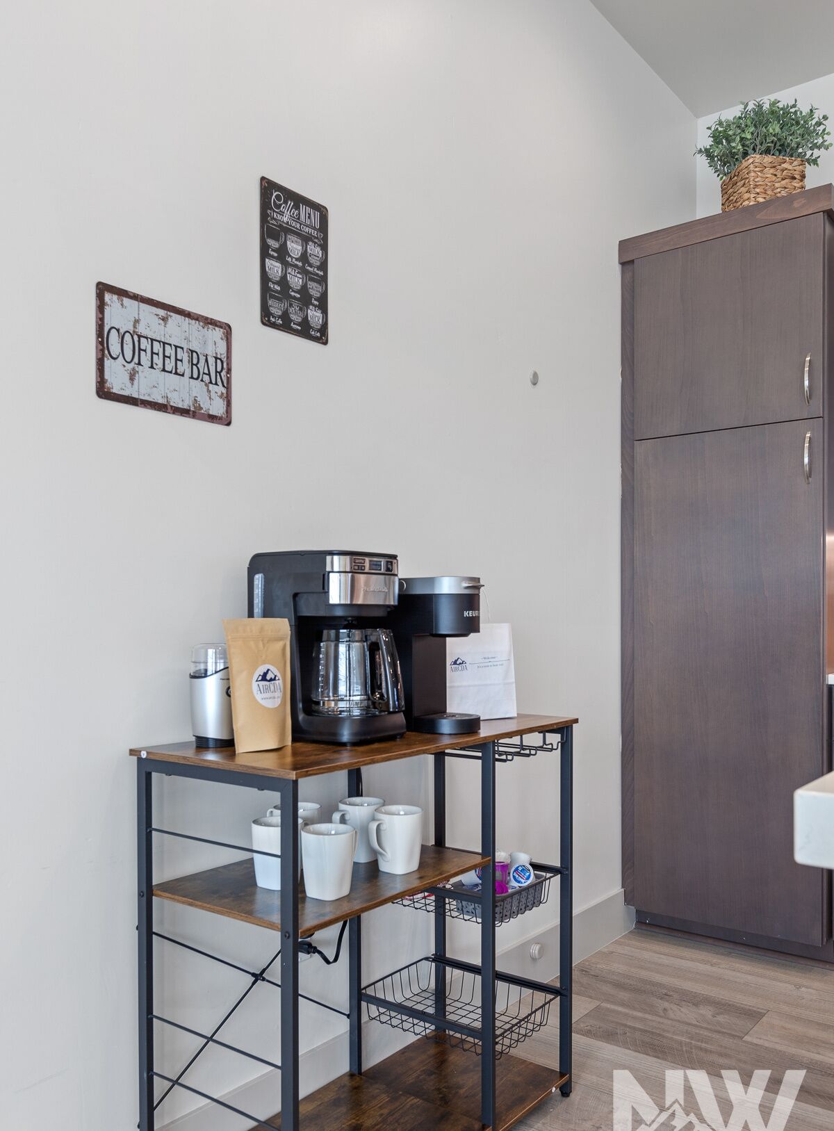 A kitchen with a coffee machine, a coffee bar sign, and a cabinet.