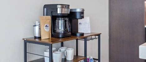 A kitchen with a coffee machine, a coffee bar sign, and a cabinet.
