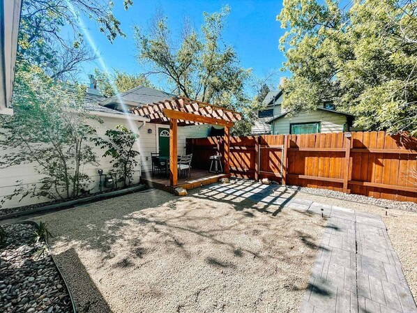 A backyard with a pergola, wooden fence, and a gravel area. - 417 E Bijou (Colorado Springs)