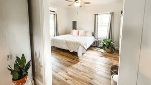 Ein Schlafzimmer mit einem Bett, einem Deckenventilator und zwei Blumentöpfen.